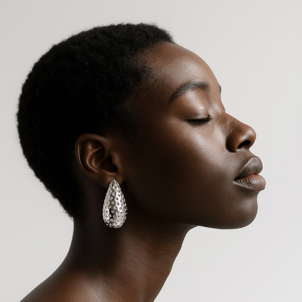Woman wearing large hoop earrings against a neutral background
