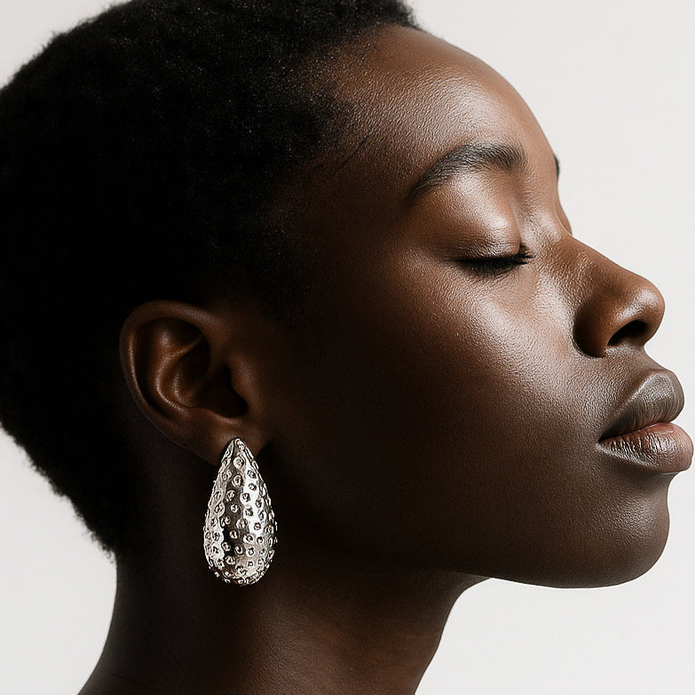 Profile of a woman wearing a sparkling earring against a neutral background