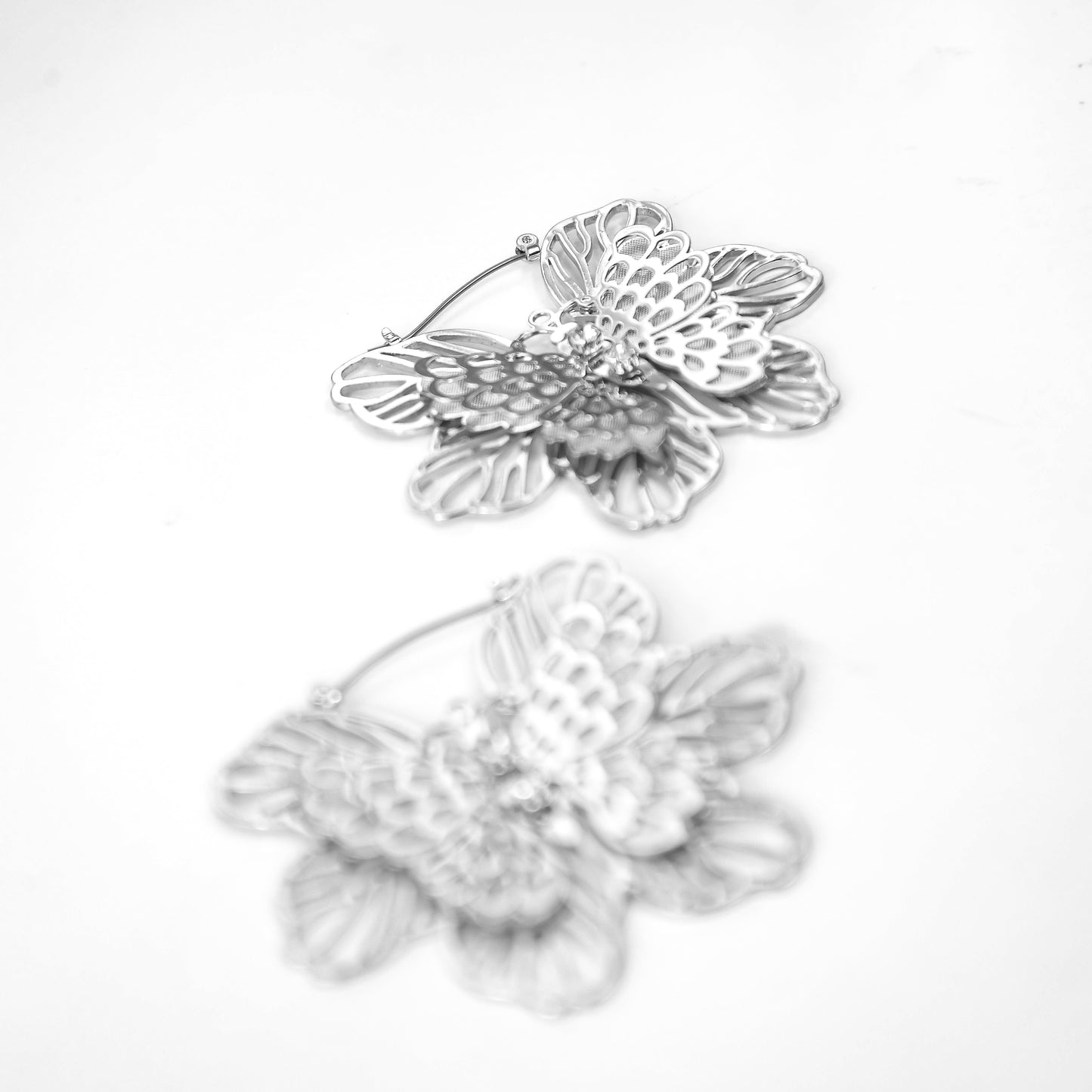 Pair of silver floral earrings on a white background