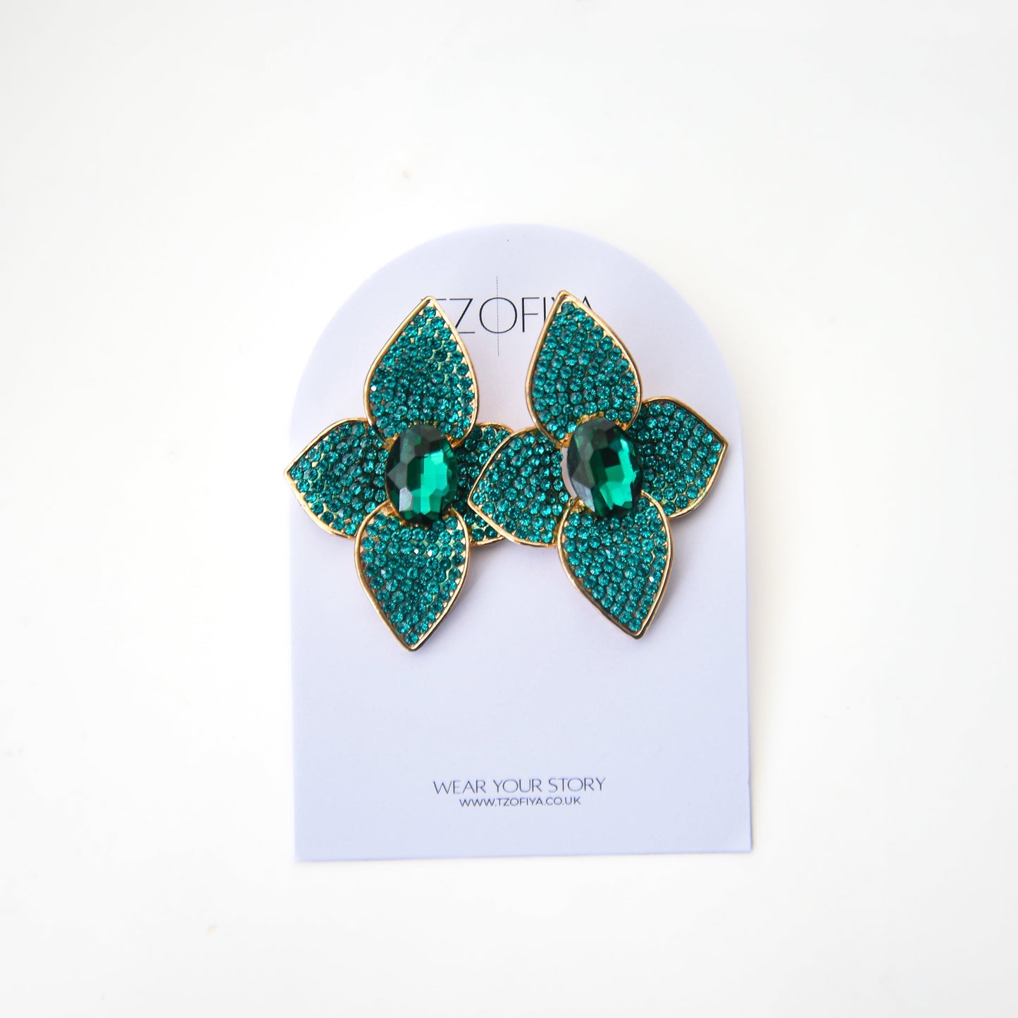 Pair of green and gold earrings on a Zoff branded card against a white background