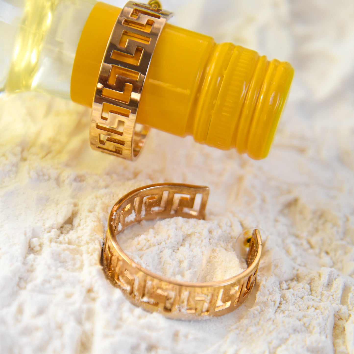 Two gold rings with a yellow cylindrical object on a textured white surface