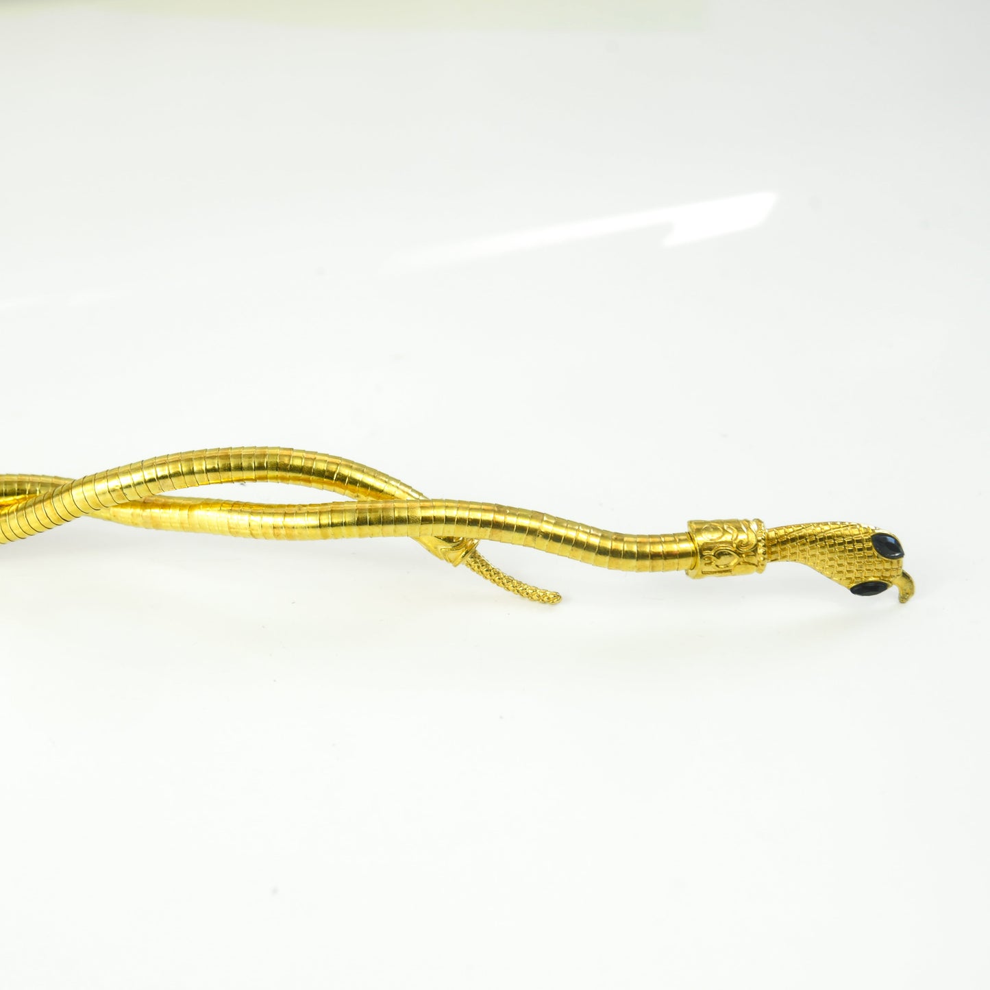 Gold-colored snake-shaped necklace on a white background