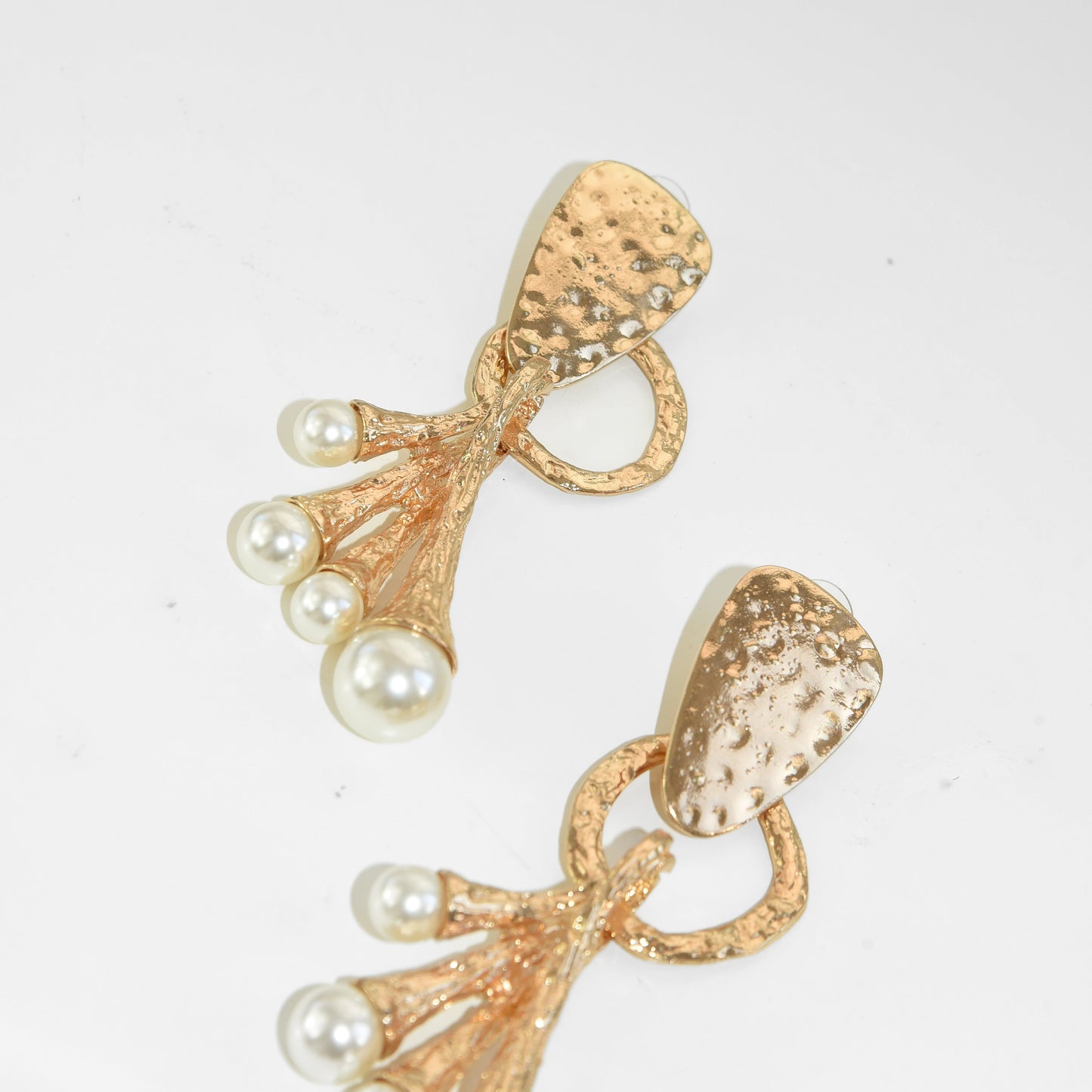 Gold earrings with pearl accents on a light gray background