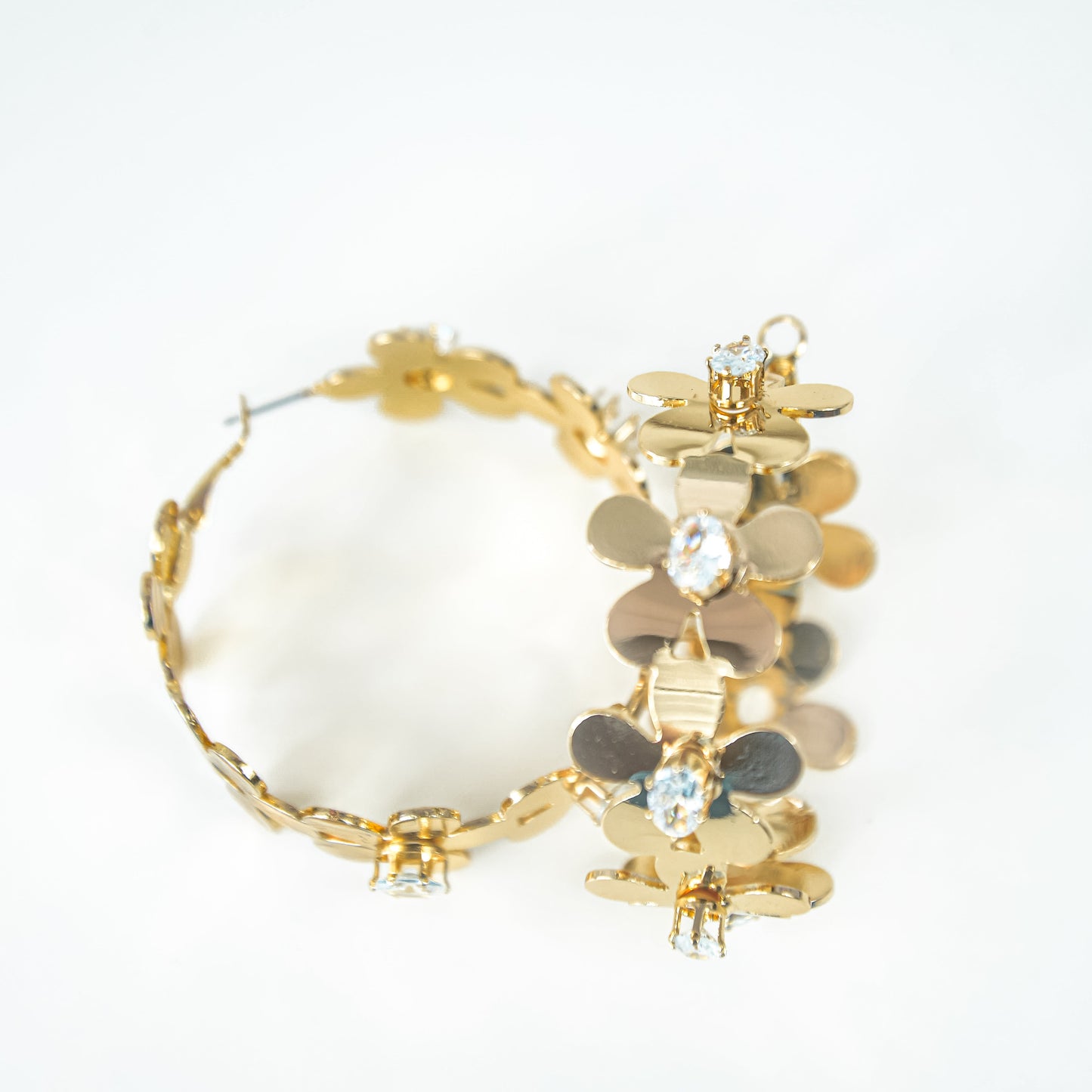 Gold hoop earrings with white stones on a white background