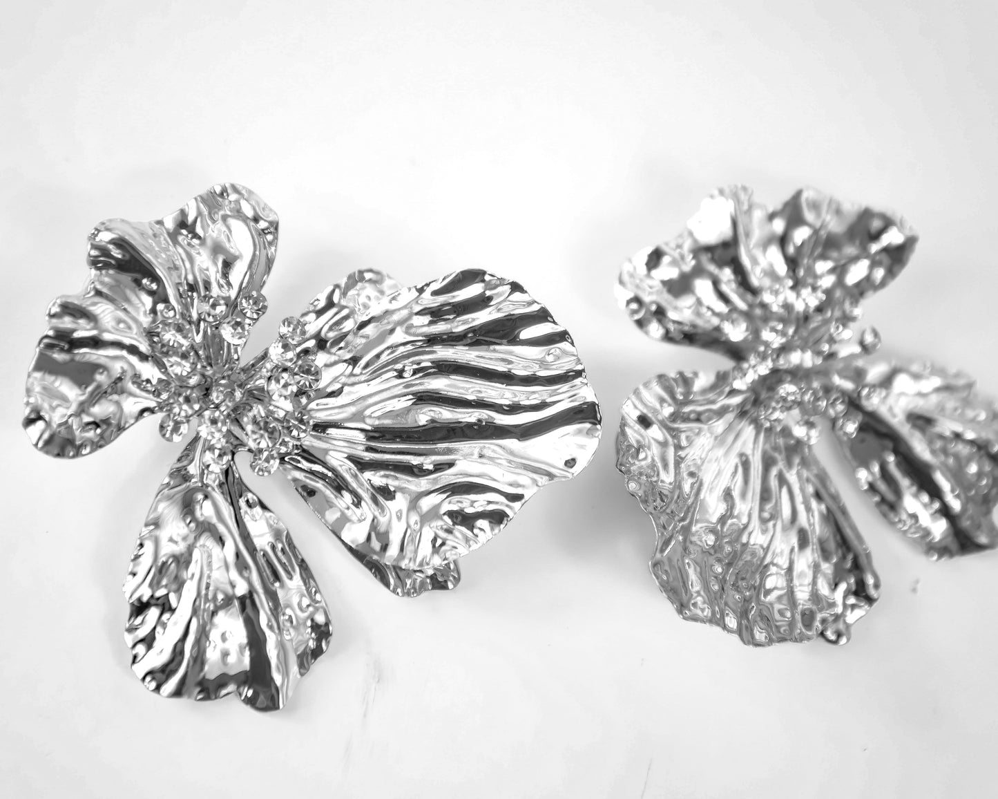 Two silver floral earrings on a light gray background