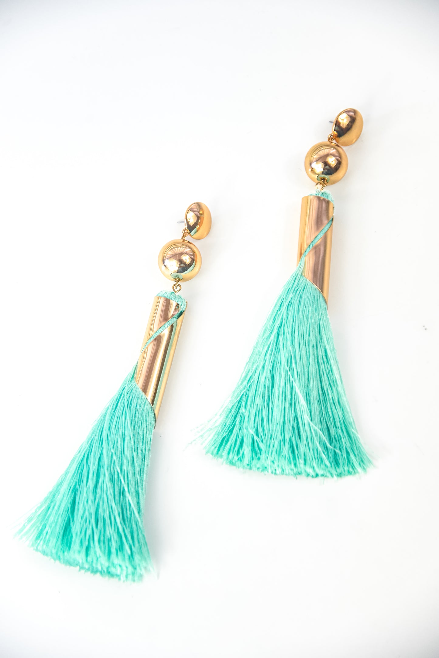 Turquoise tassel earrings with gold accents on a white background