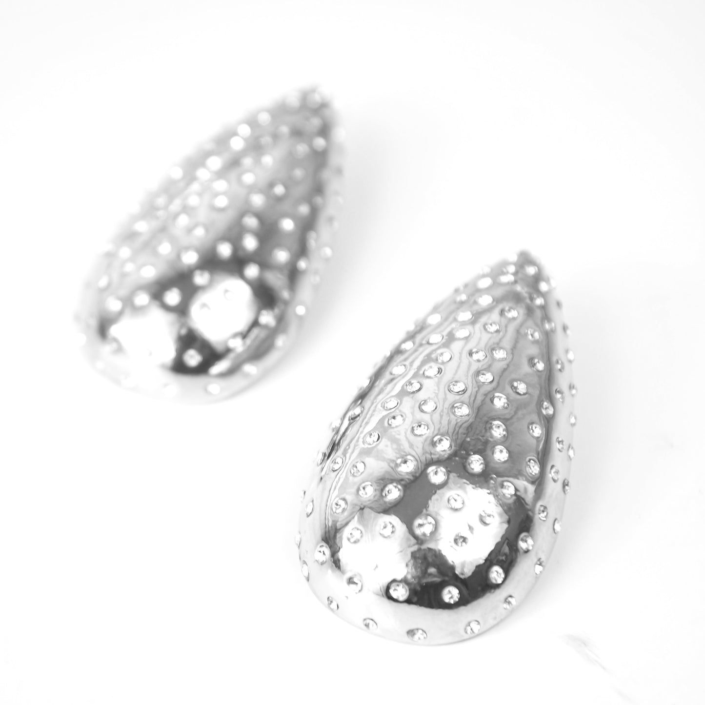 Teardrop-shaped silver earrings with a textured surface on a white background