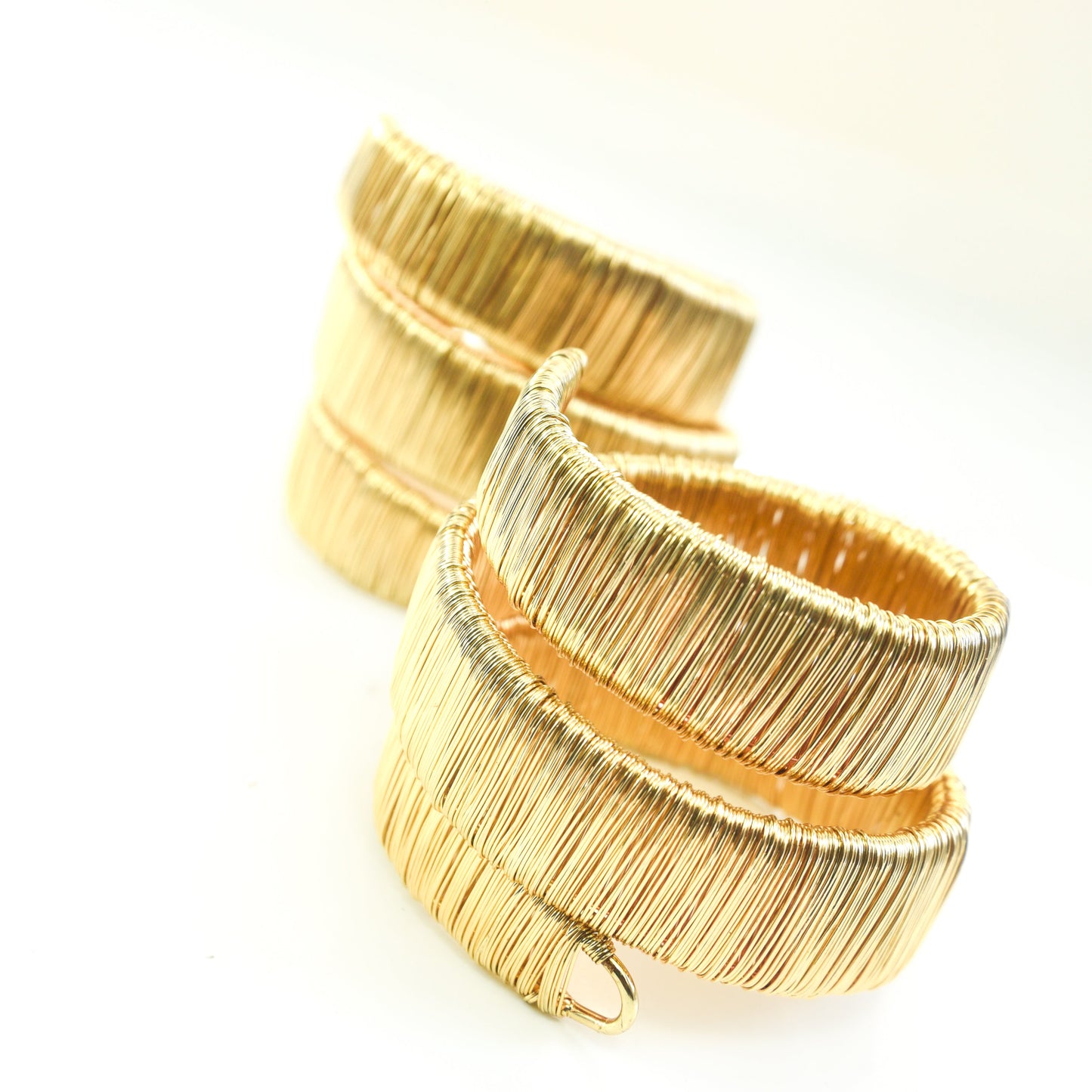 Two gold bracelets on a white background