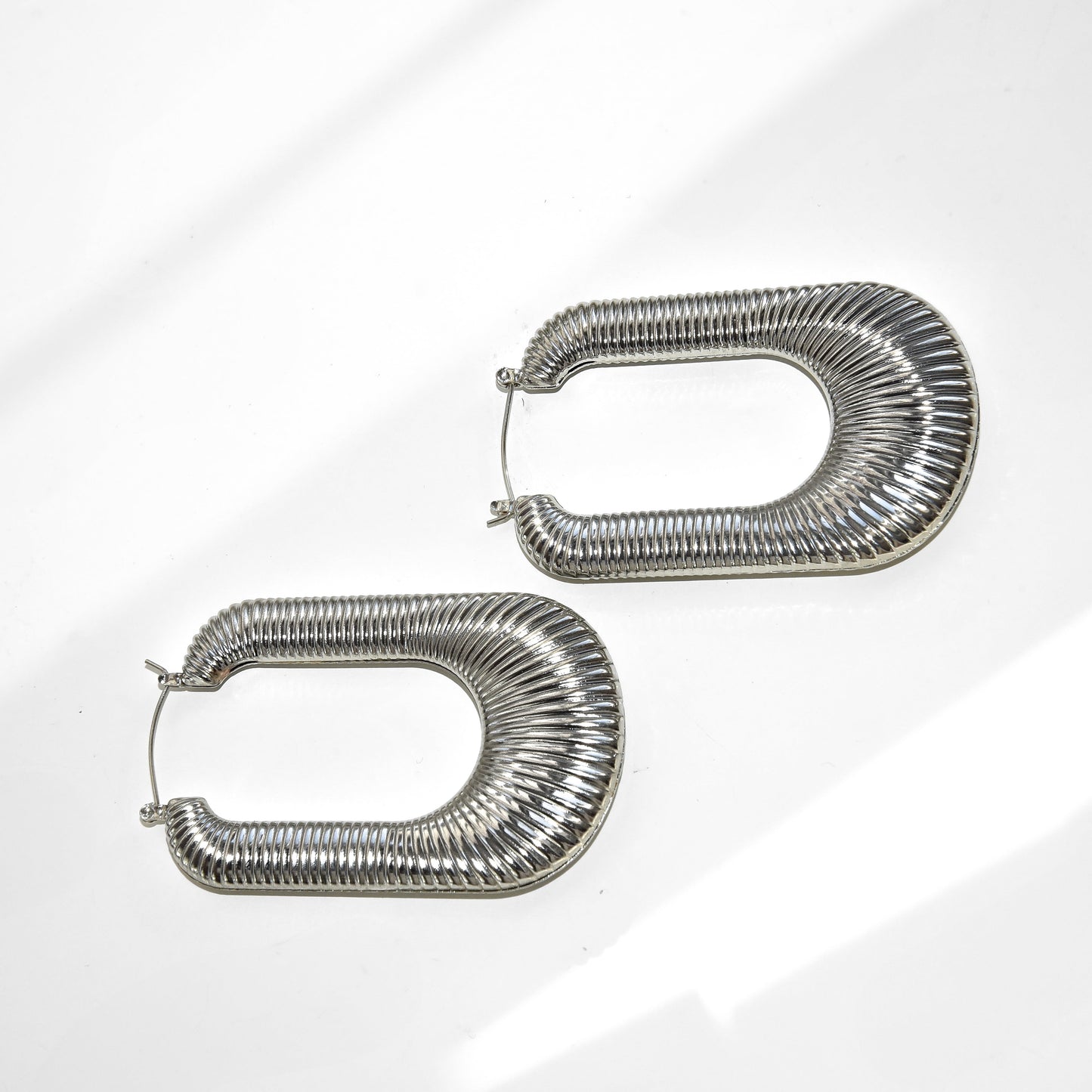 Pair of silver hoop earrings on a light gray background