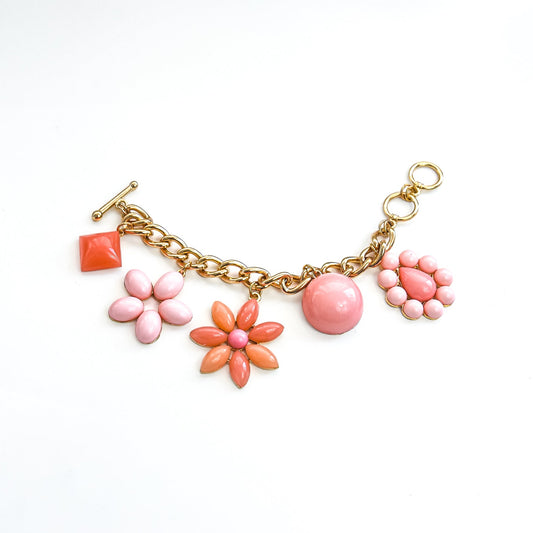 Gold bracelet with pink flower charms on a white background
