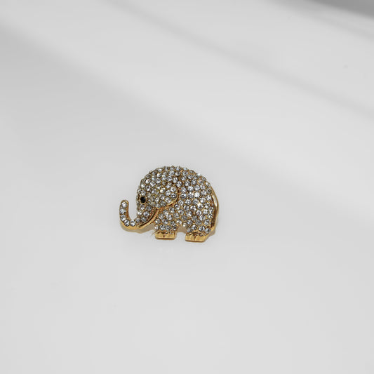 Gold elephant-shaped brooch with gemstones on a white background