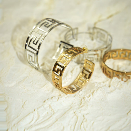 Gold hoop earrings on a textured white surface