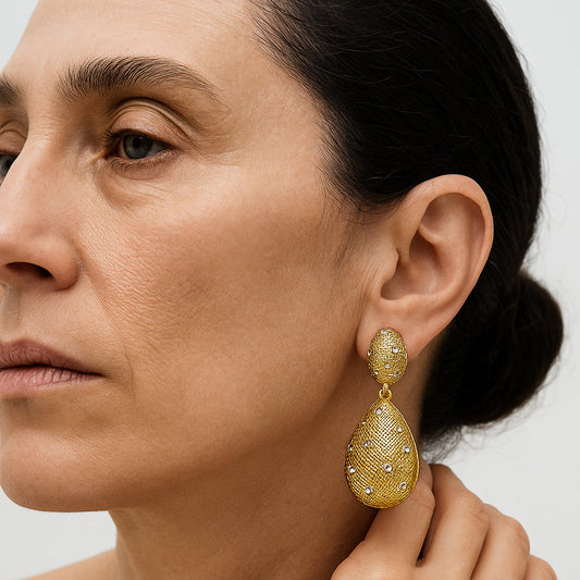 Woman wearing gold earrings with a neutral background