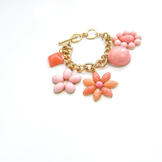 Gold bracelet with pink and orange flower charms on a white background