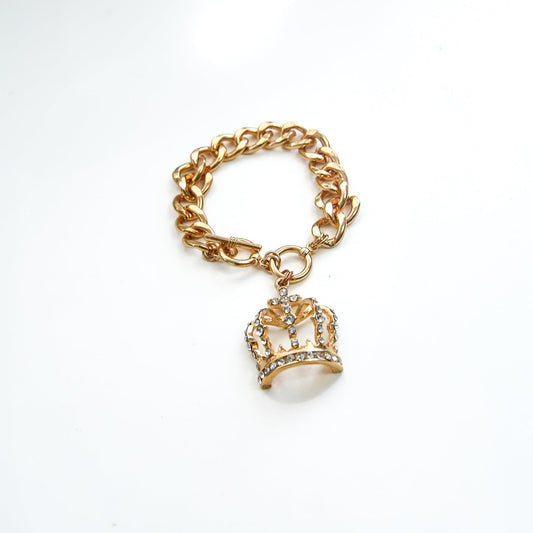 Gold bracelet with a crown charm on a white background