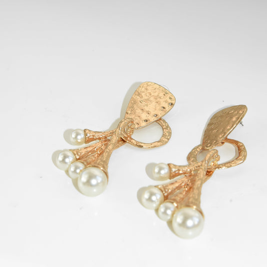 Gold earrings with pearl accents on a light gray background