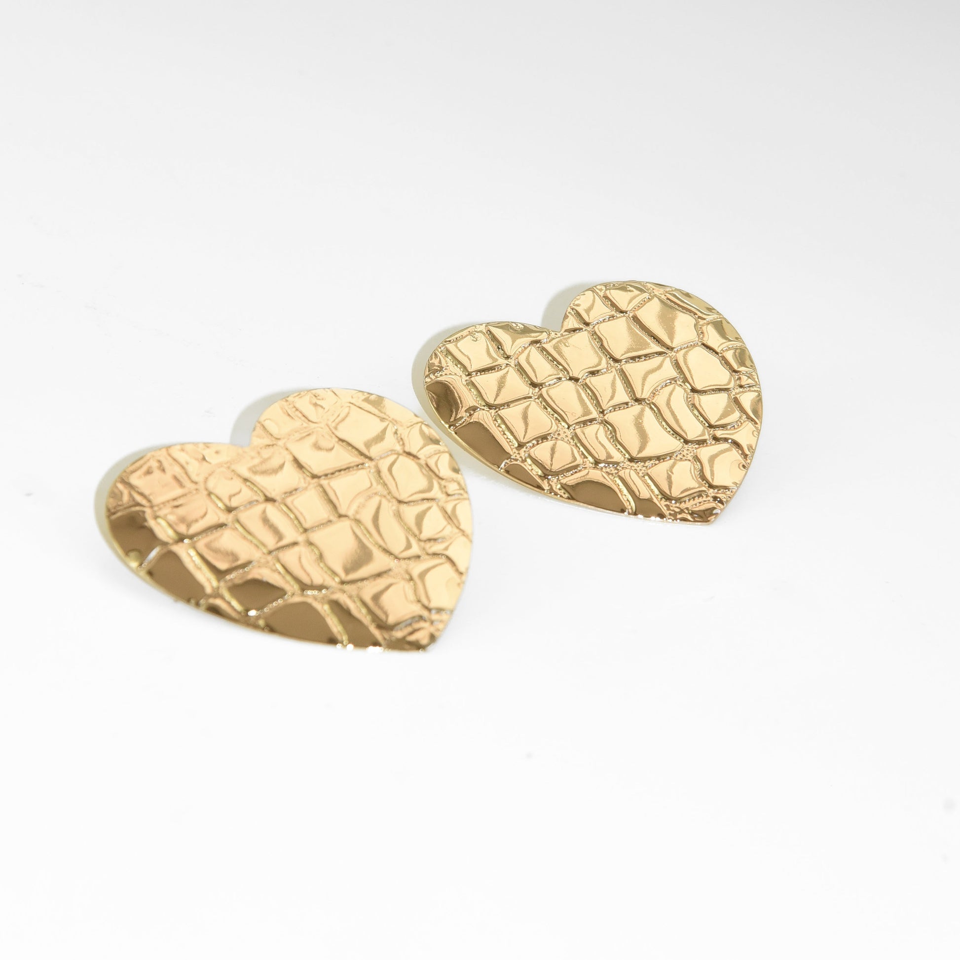 Gold textured heart-shaped earrings on a white background