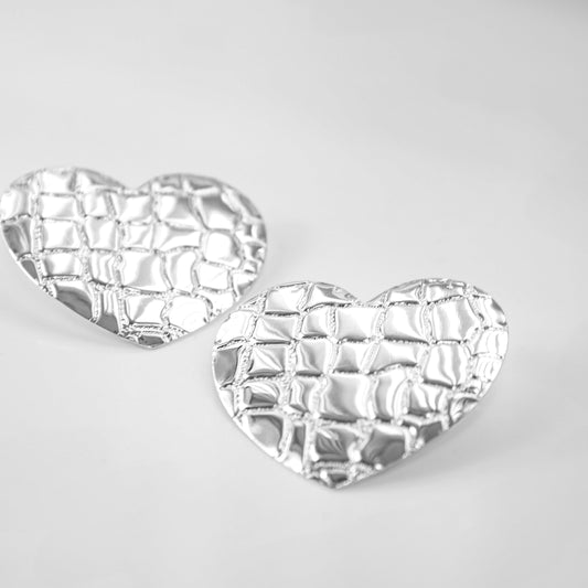 Heart-shaped silver earrings on a light gray background