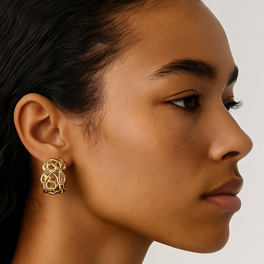 Close-up of a woman wearing gold earrings against a neutral background