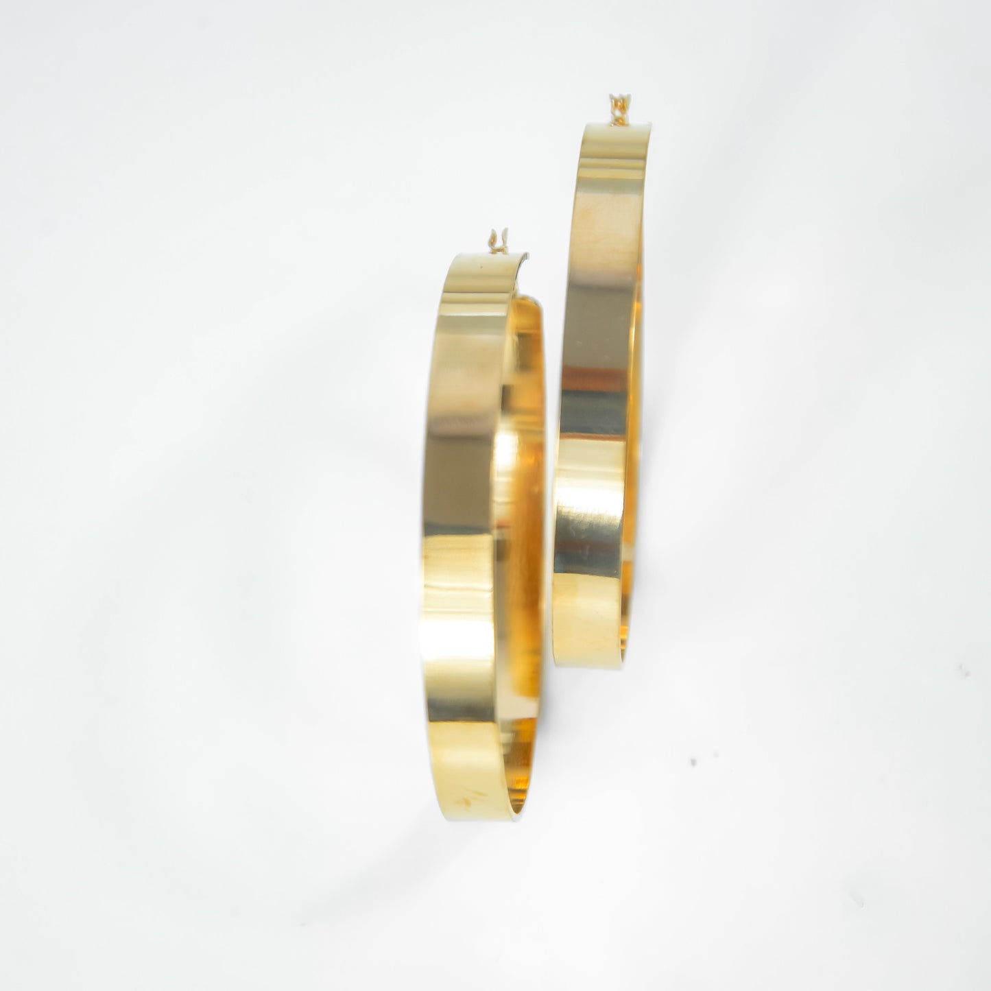 Two gold hoop earrings on a white background