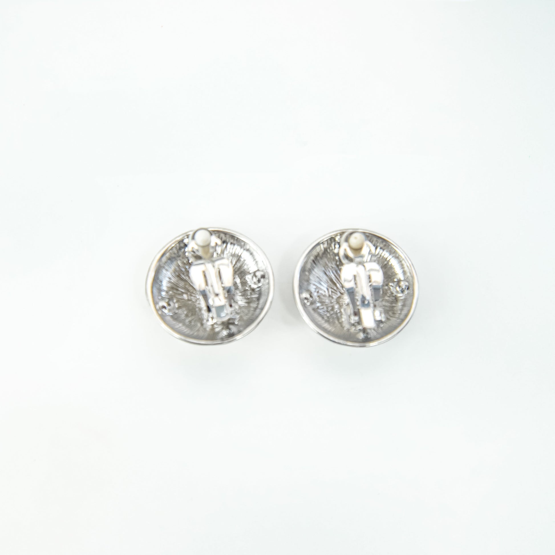 Pair of silver earrings with clear gemstones on a white background