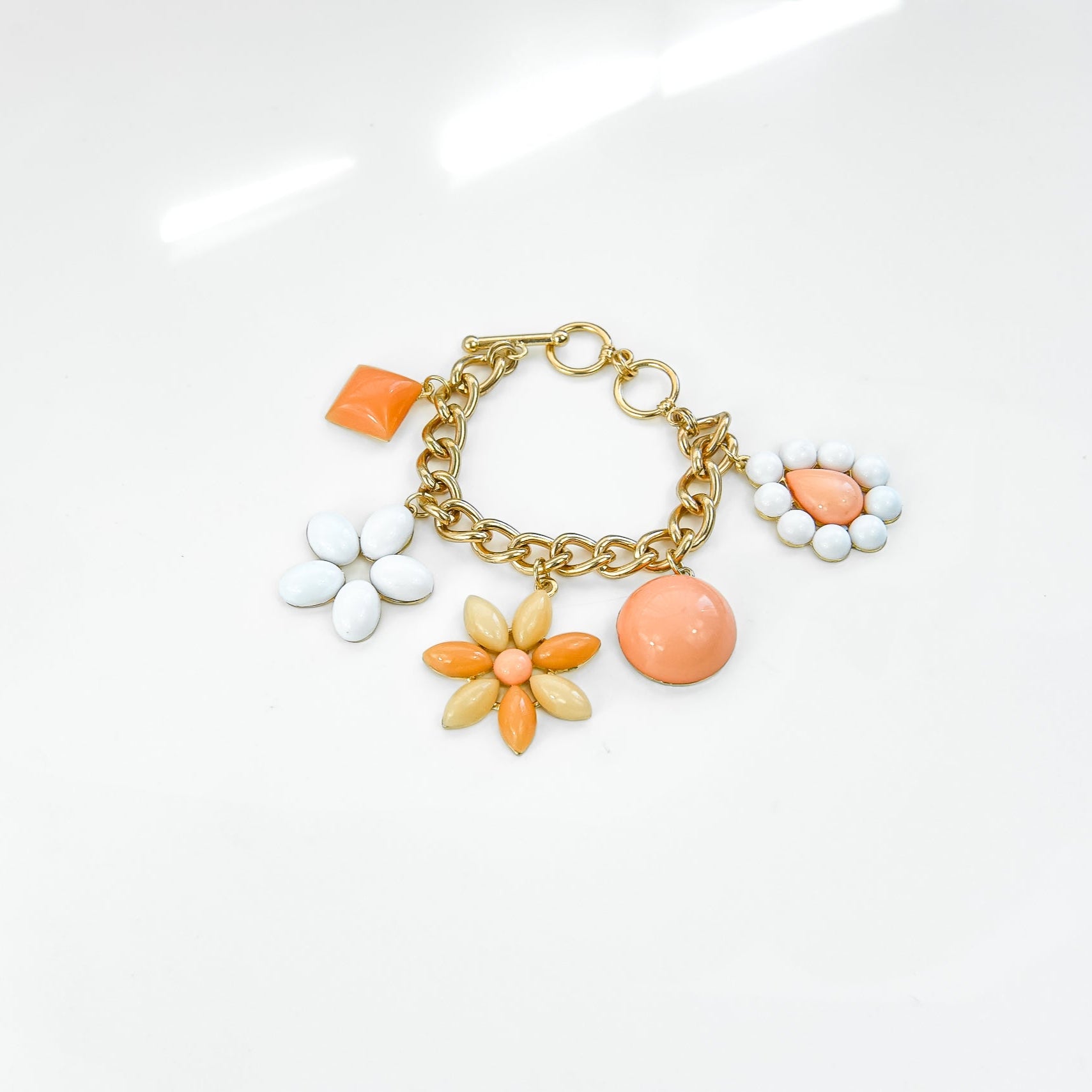 Gold bracelet with colorful charms on a white background